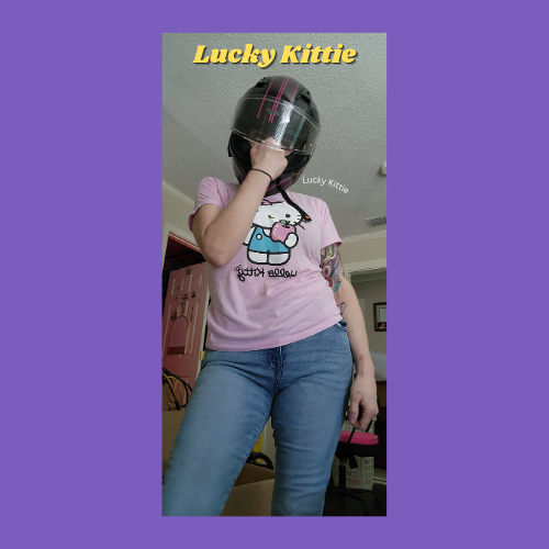 Indiecammodels FemDom cam model Lucky Kittie standing in jeans, motorcycle helmet and a hello kitty tee shirt