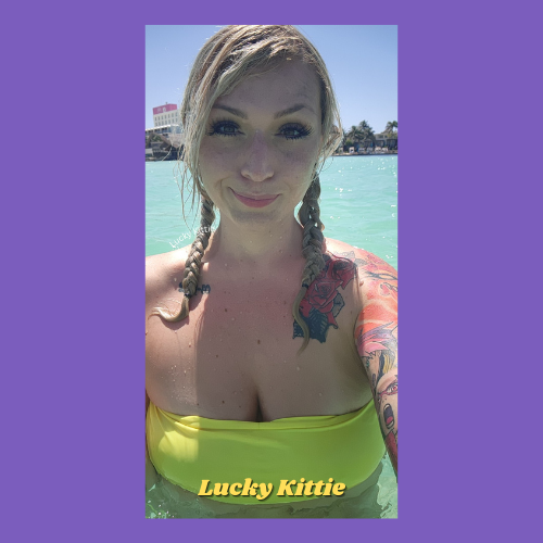 Indiecammodels FemDom cam model Lucky Kittie IndieCamFans standing in water wearing a neon green bikini top and pigtails.