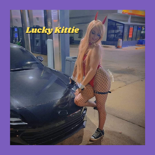 Indiecammodels FemDom cam model Lucky Kittie of IndieCamFans in fishnets, a teddy and devil ears standing beside her car at a gas station.