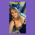 Indiecammodels mature cam model of IndieCamFans.com Velvet Skye lounging in a black lace bra with her blonde hair laying pretty on her face, a sexy smile on her face.